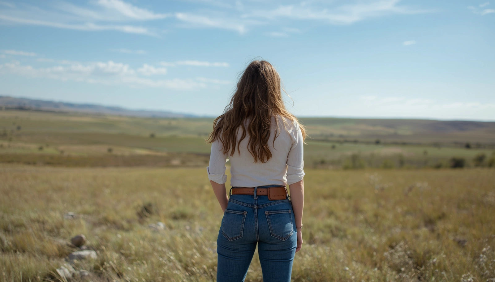 Person standing in a field looking at a vast landscape